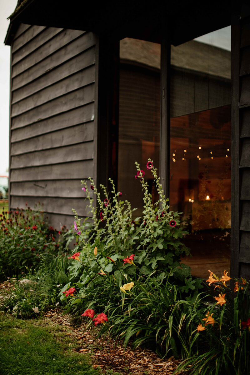 Red and yellow flowers outside rustic barn at scenic wedding venue.