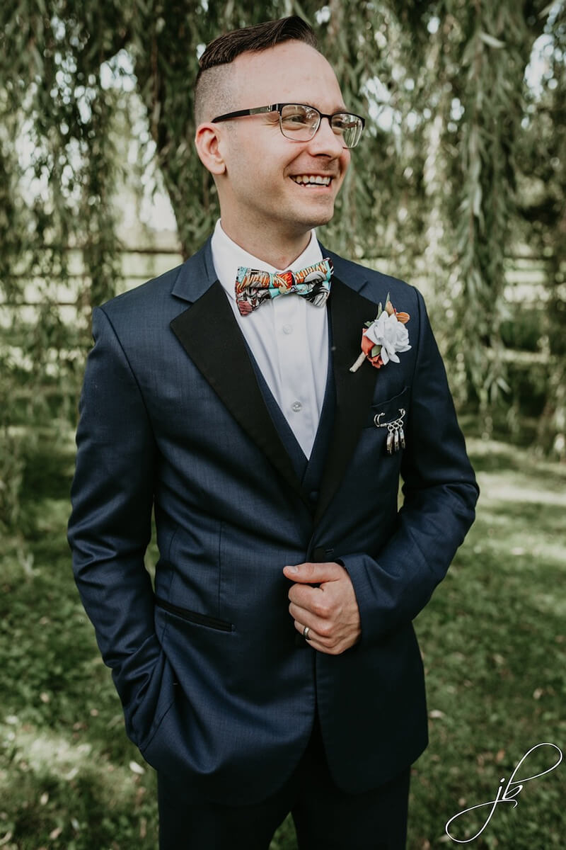 Groom standing in scenic green pasture at Providence Barn.