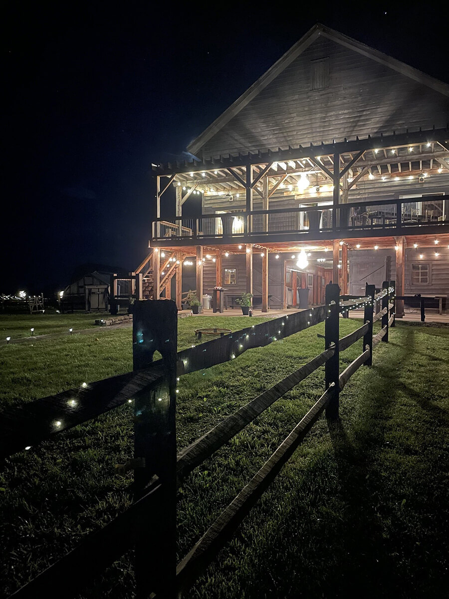 Large rustic barn deck lit up during night.