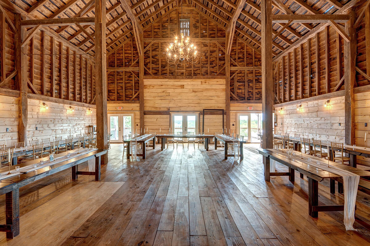 Scenic zoomed out shot of rustic barn venue with tables and chandelier.