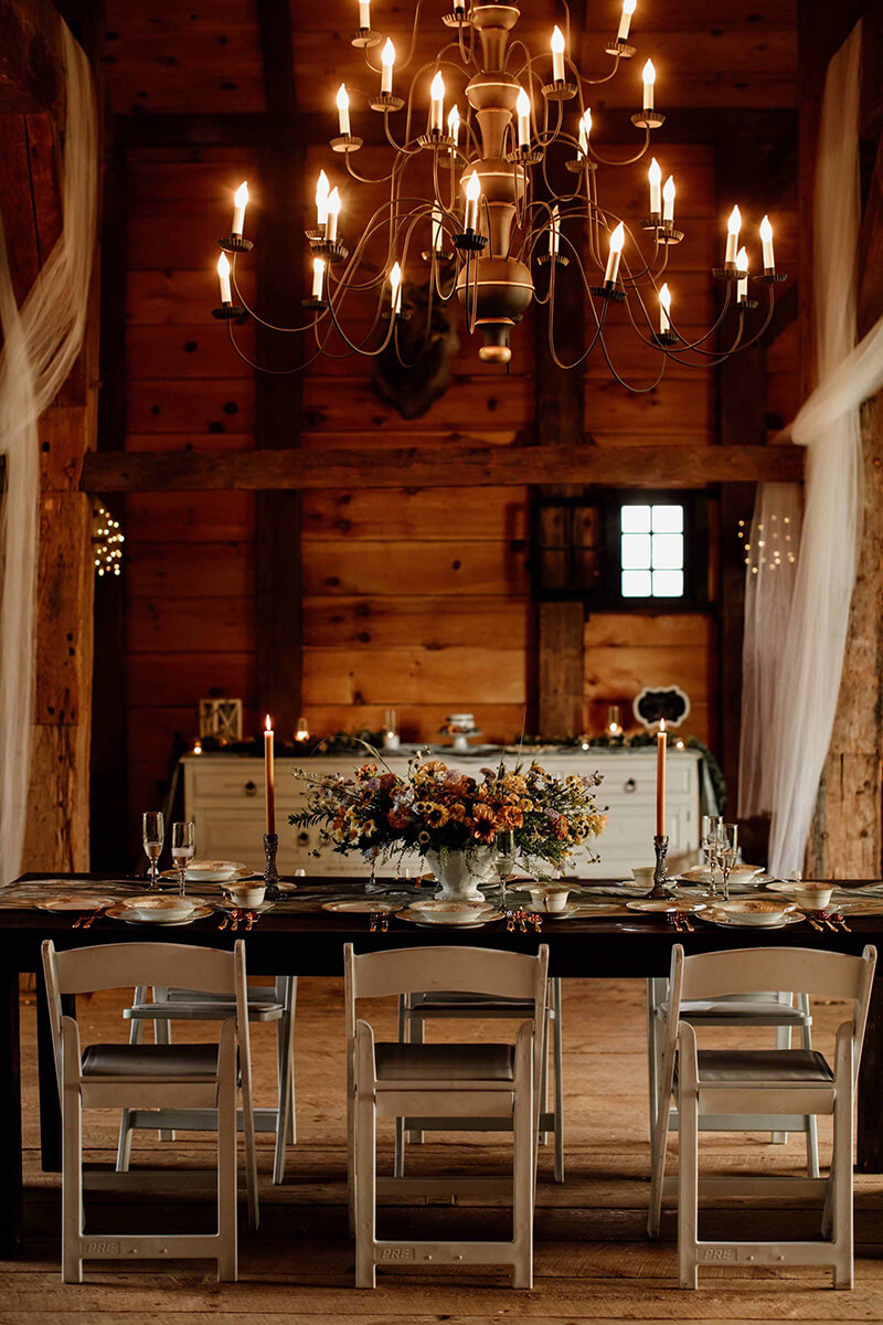 Interior of rustic barn set up for dinner with beautiful chandelier.