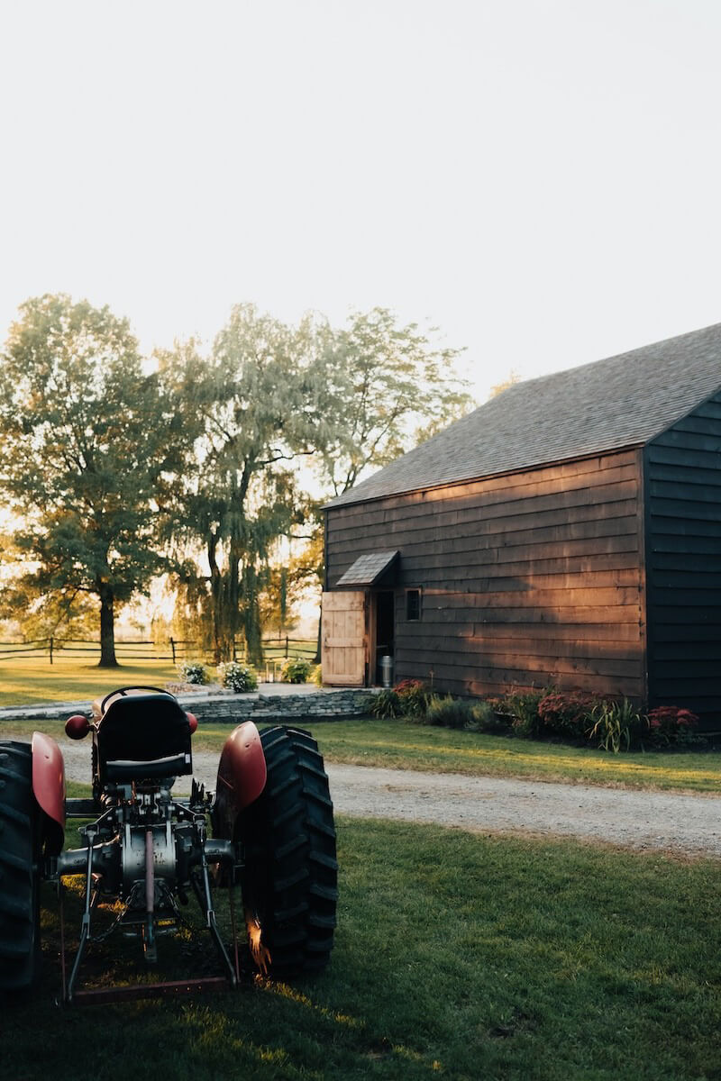 Scenic view of tractor in sunset at rustic barn with willow trees.