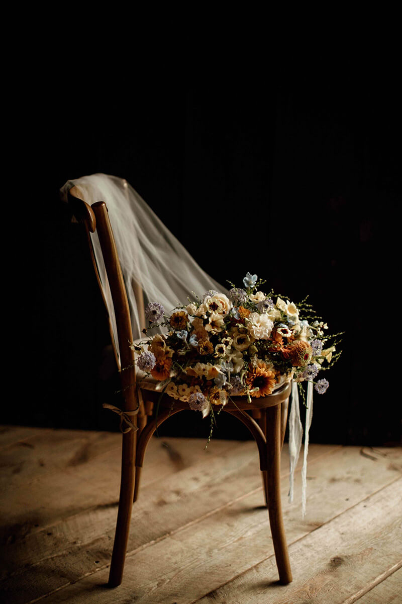 Wooden chair with wedding veil and beautiful floral arrangement.